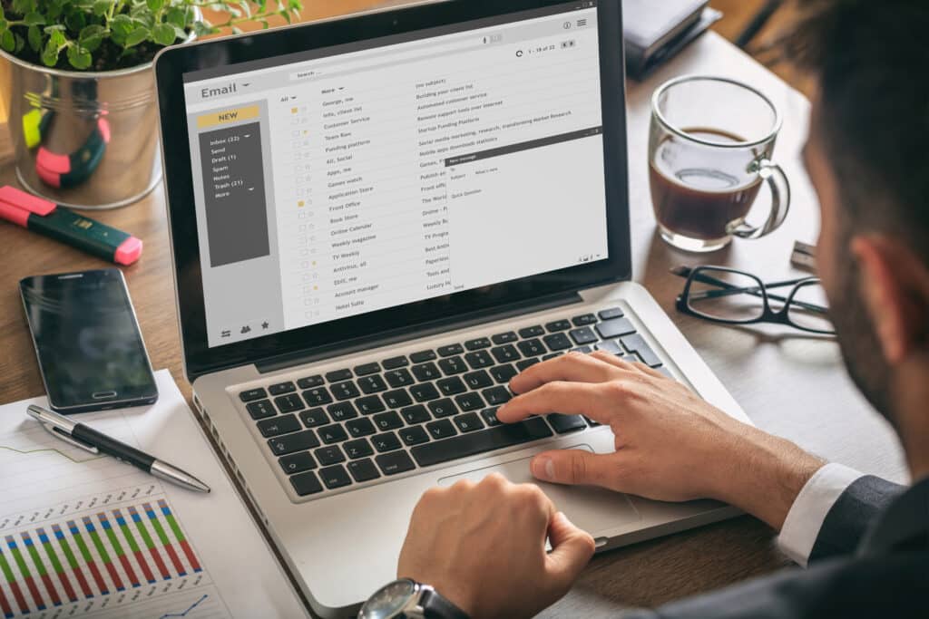 Emails list on a laptop screen, office background Practice secure email practices to avoid Business Email Compromise